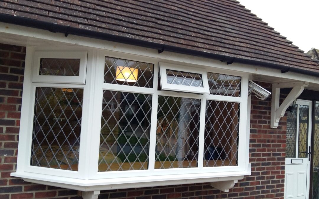 Exterior view of a house rear showing a white‑framed conservatory or glazed extension with multiple UPVC windows and doors.